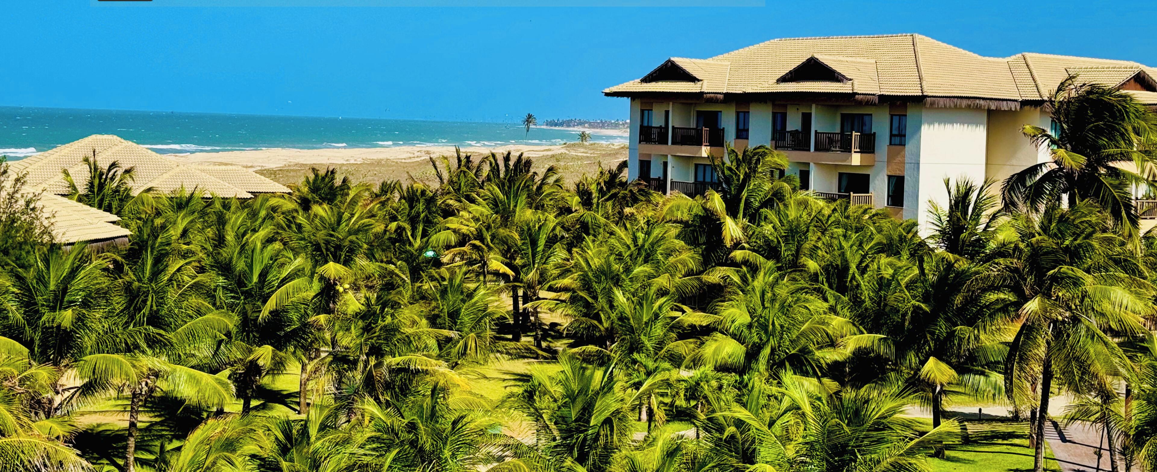 Ein Hotel mit Blick auf den Strand, umgeben von Palmen.