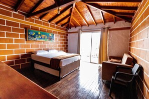Un dormitorio con cama, una silla y un cuadro en la pared.