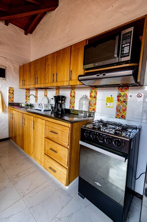 Una cocina con gabinetes de madera, estufa a gas, microondas y salpicadero de azulejos.