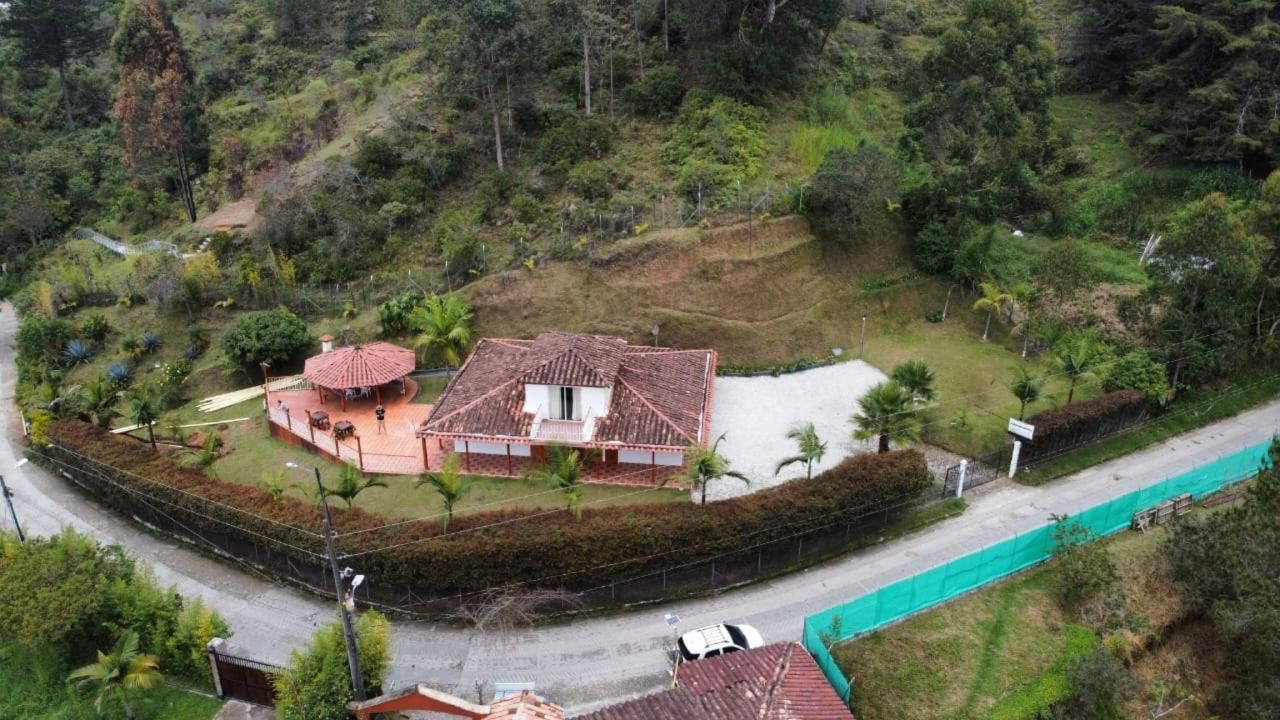 Una casa con tejado de baldosas, rodeada de abundante vegetación y una cerca.