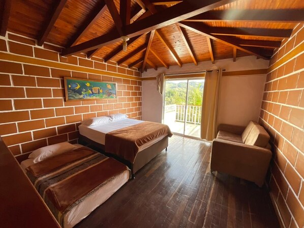 Una habitación con cama, sofá, sillón y balcón con vistas.