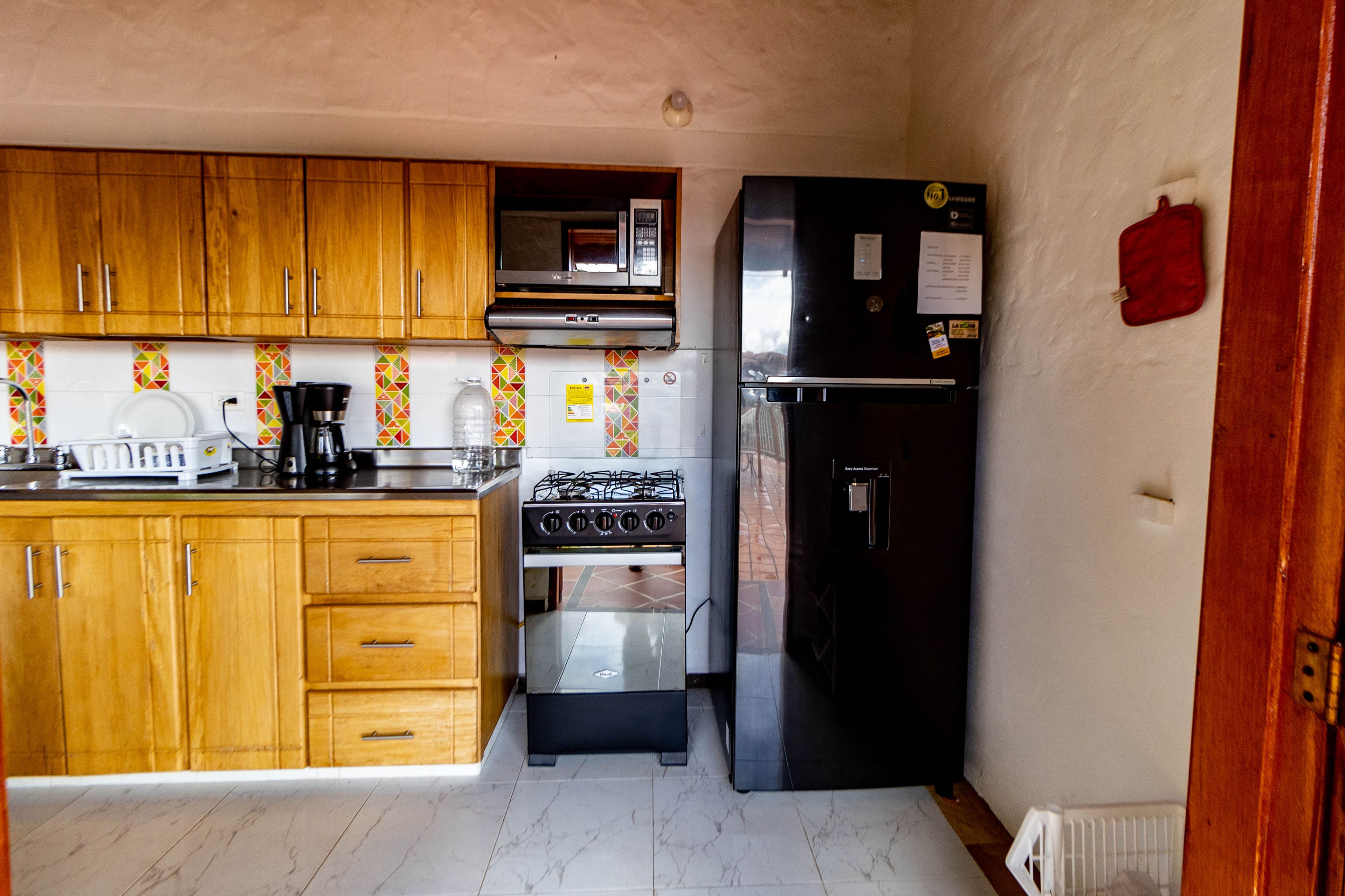 A compact kitchen with wooden cabinets, a microwave, a gas stove, and a black refrigerator.