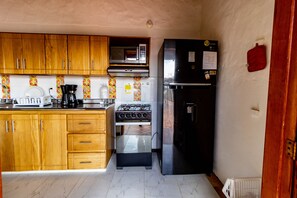 A compact kitchen with wooden cabinets, a microwave, a gas stove, and a black refrigerator.