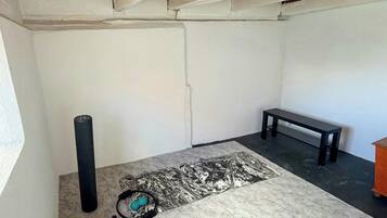 A room with a wooden ceiling, a bench, a yoga mat, and exercise equipment.