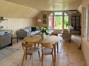 A cozy cabin interior with a dining area, sofa, and kitchen.