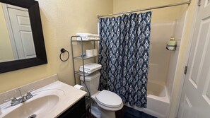 Un baño con lavamanos, inodoro y cortina de ducha blancos.