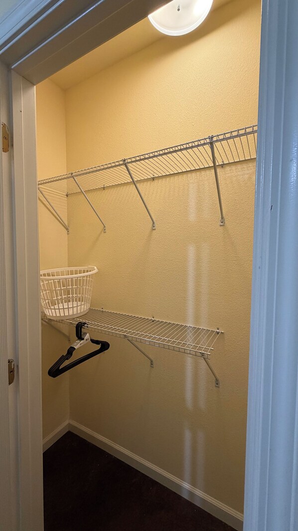Un espace dédié à la lessive, avec des étendoirs métalliques et un panier blanc.