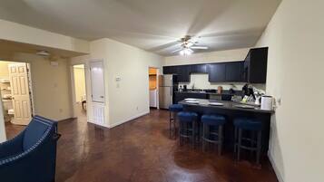 A spacious kitchen with a central island, dark cabinets, and a ceiling fan.