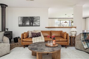 Una sala de estar acogedora con un sofá de cuero, una mesa de centro, una chimenea y un cuadro en la pared.