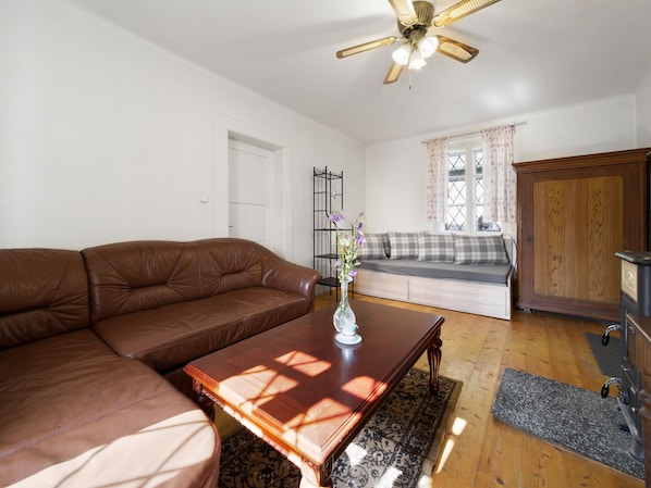 A living room with a brown leather sofa, a wooden coffee table, a floor lamp, and a window with curtains.