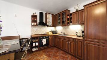 Una cocina con armarios de madera, estufa, microondas y fregadero.