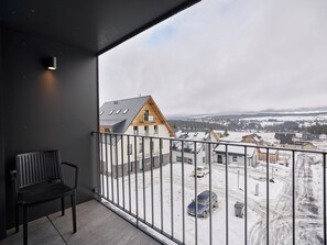 A balcony with a view of a snow-covered landscape and a wooden house. - Apartment Lagom by Interhome (Abertamy)