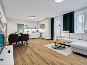 A modern living room with a sofa, a dining table with chairs, a kitchen area, and a large window with curtains. - Apartment Lagom by Interhome (Abertamy)