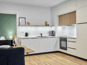 Une cuisine moderne avec des meubles blancs, un four encastré et une machine à café.