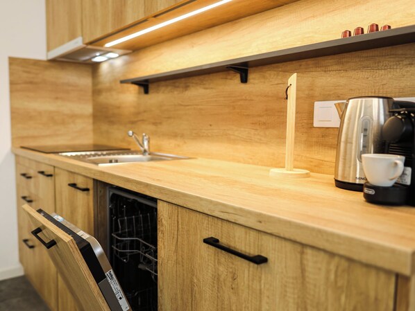 Une cuisine moderne avec des meubles en bois, une machine à café en acier inoxydable et un lave-vaisselle.