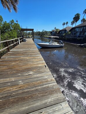 A wooden dock extending into calm water with a boat moored at the end. - 1-bedroom loft bungalow, boat dock, pool, Crystal River access (Crystal River)