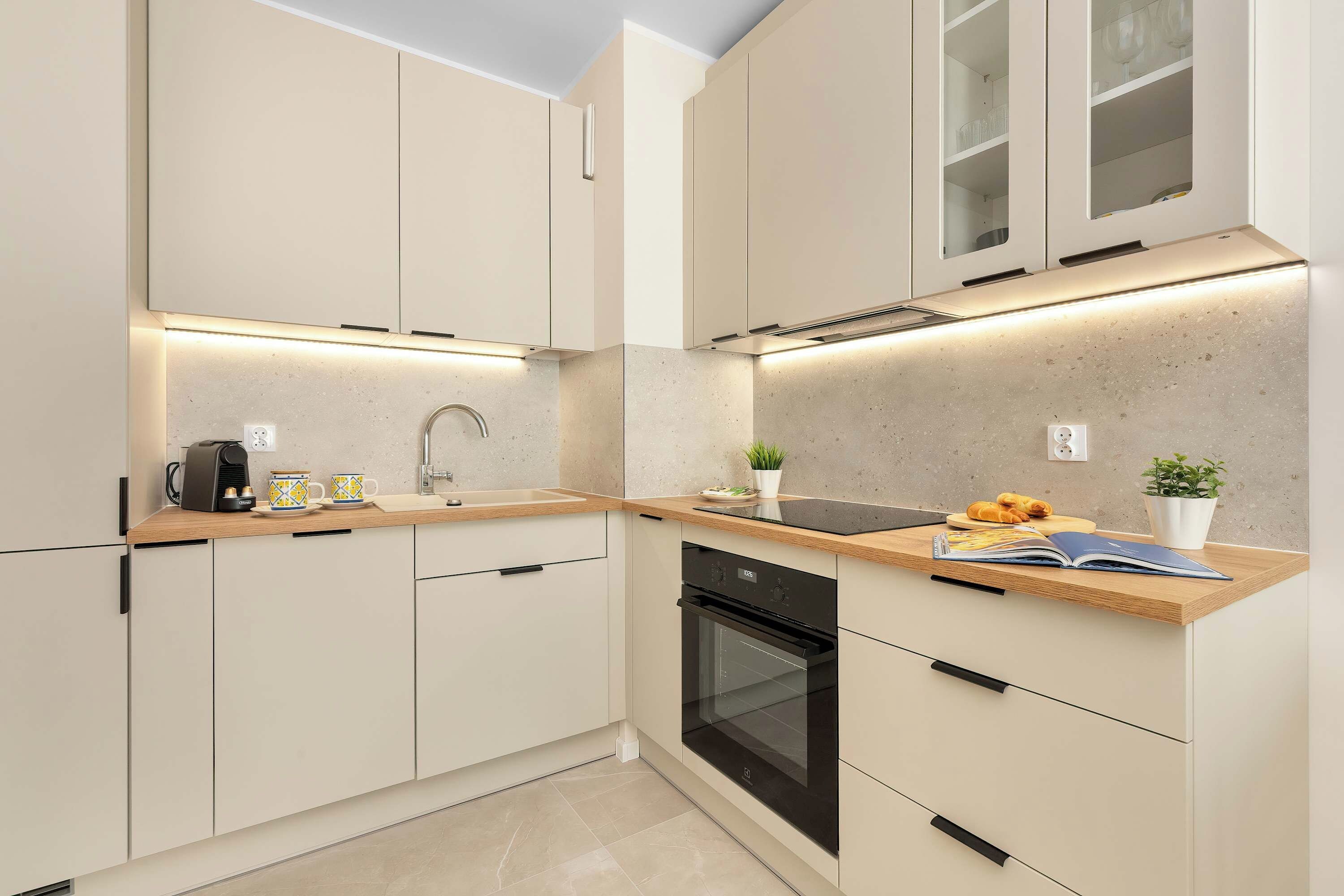 Functional kitchenette with cabinetry, integrated appliances and a light wooden worktop.