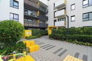 Een meerlaags woongebouw met balkons, een verhard voetpad en groen.