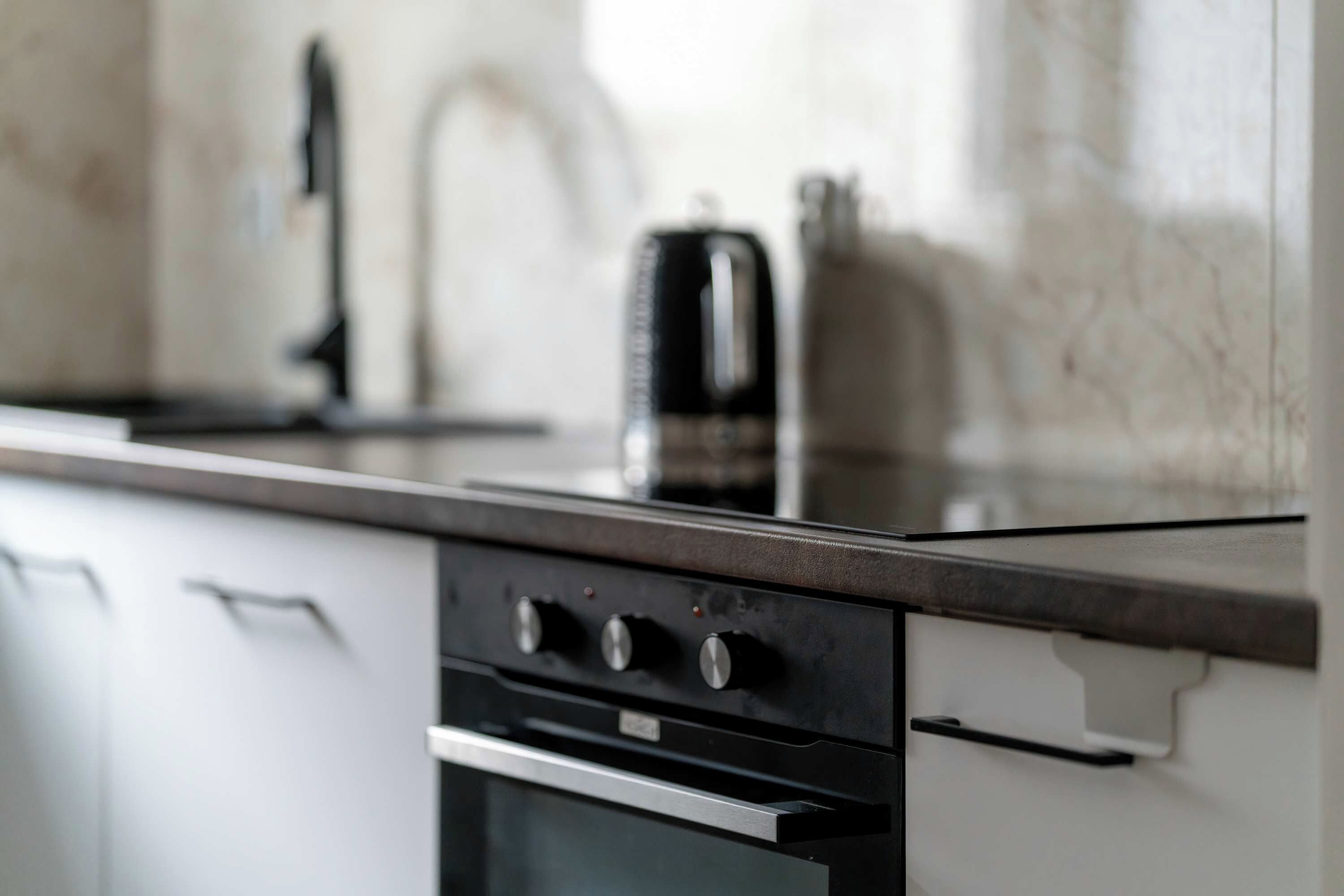 Een keuken met een modern ontwerp, met een roestvrijstalen oven en een zwart aanrecht.