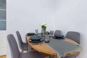 A dining table set with plates, glasses, and a vase with flowers. - Panoramic Sea View Apartment | 2 Bedrooms (Gdańsk)