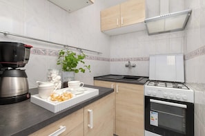 A modern kitchen with a gas stove, a coffee maker, a kettle, and a plant. - Panoramic Sea View Apartment | 2 Bedrooms (Gdańsk)