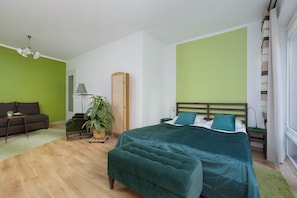Ein Schlafzimmer mit einem Bett, einem Sofa, einer Lampe und einer Pflanze.