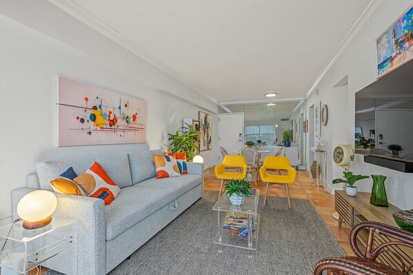 A modern living room with a grey sofa, yellow chairs, and a glass coffee table. - Serene 1-bedroom condo in beautiful Key Biscayne, 3 minute walk to the beach (Key Biscayne)
