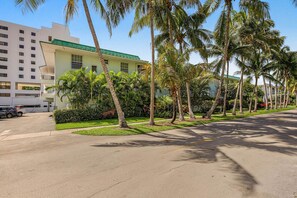 A street lined with palm trees and a building with a green roof. - Serene 1-bedroom condo in beautiful Key Biscayne, 3 minute walk to the beach (Key Biscayne)