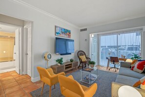 A living room with a TV, seating, and a view of the outside. - Serene 1-bedroom condo in beautiful Key Biscayne, 3 minute walk to the beach (Key Biscayne)