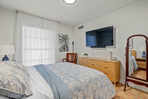 A bedroom with a bed, a dresser, a chair, a television, and a mirror. - Serene 1-bedroom condo in beautiful Key Biscayne, 3 minute walk to the beach (Key Biscayne)