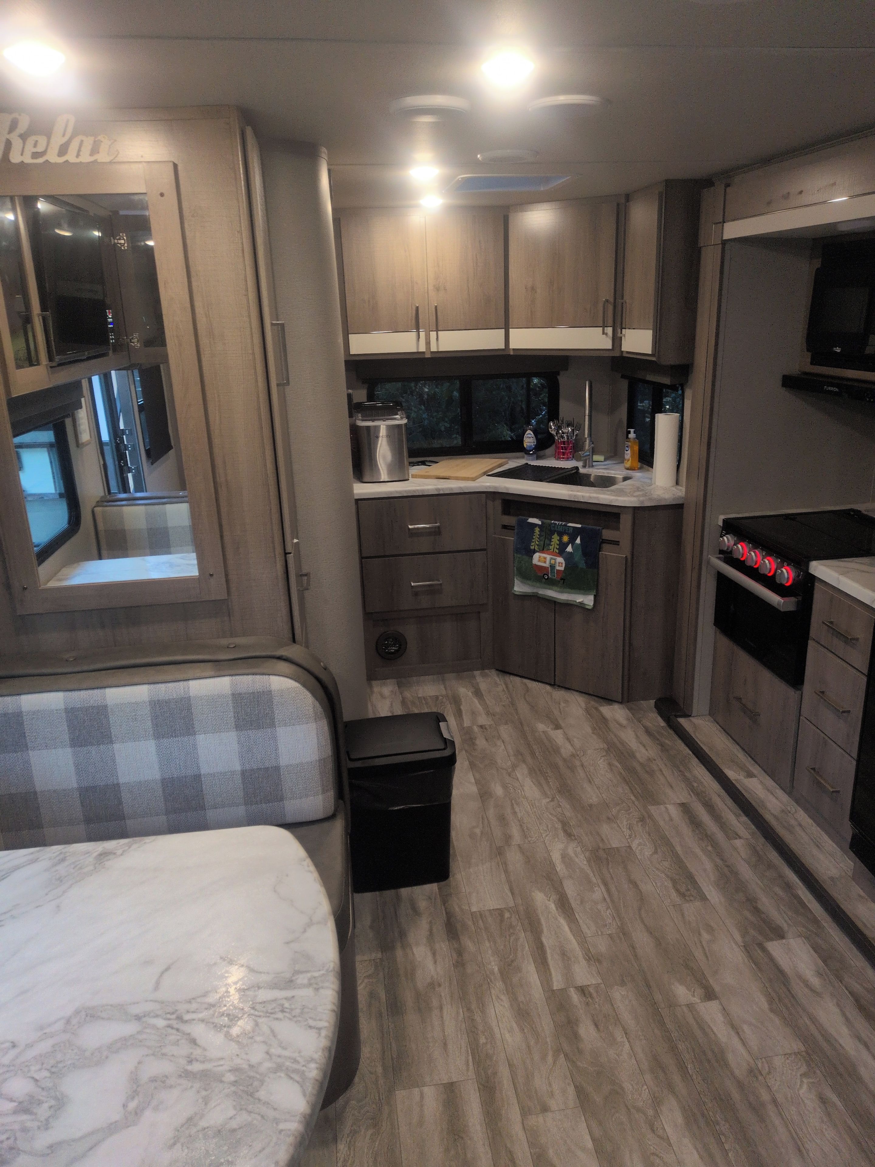A compact RV kitchen with a microwave, sink, and stove.