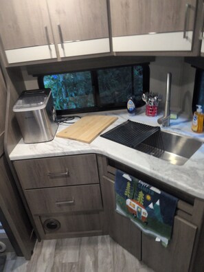 A compact kitchen with a built-in sink, a toaster, and a cutting board.