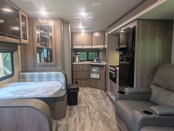 Ein kompaktes Wohnmobil-Interieur mit einer Küchenzeile, einem Essbereich und einer Sitzecke.