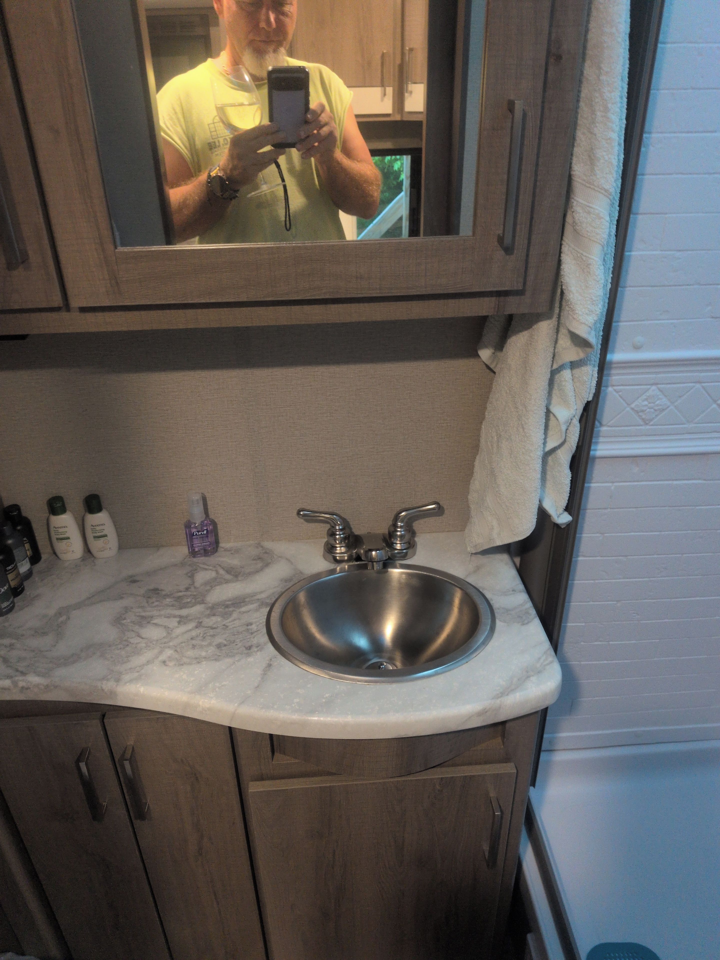 A bathroom with a sink, mirror, and wooden cabinets.