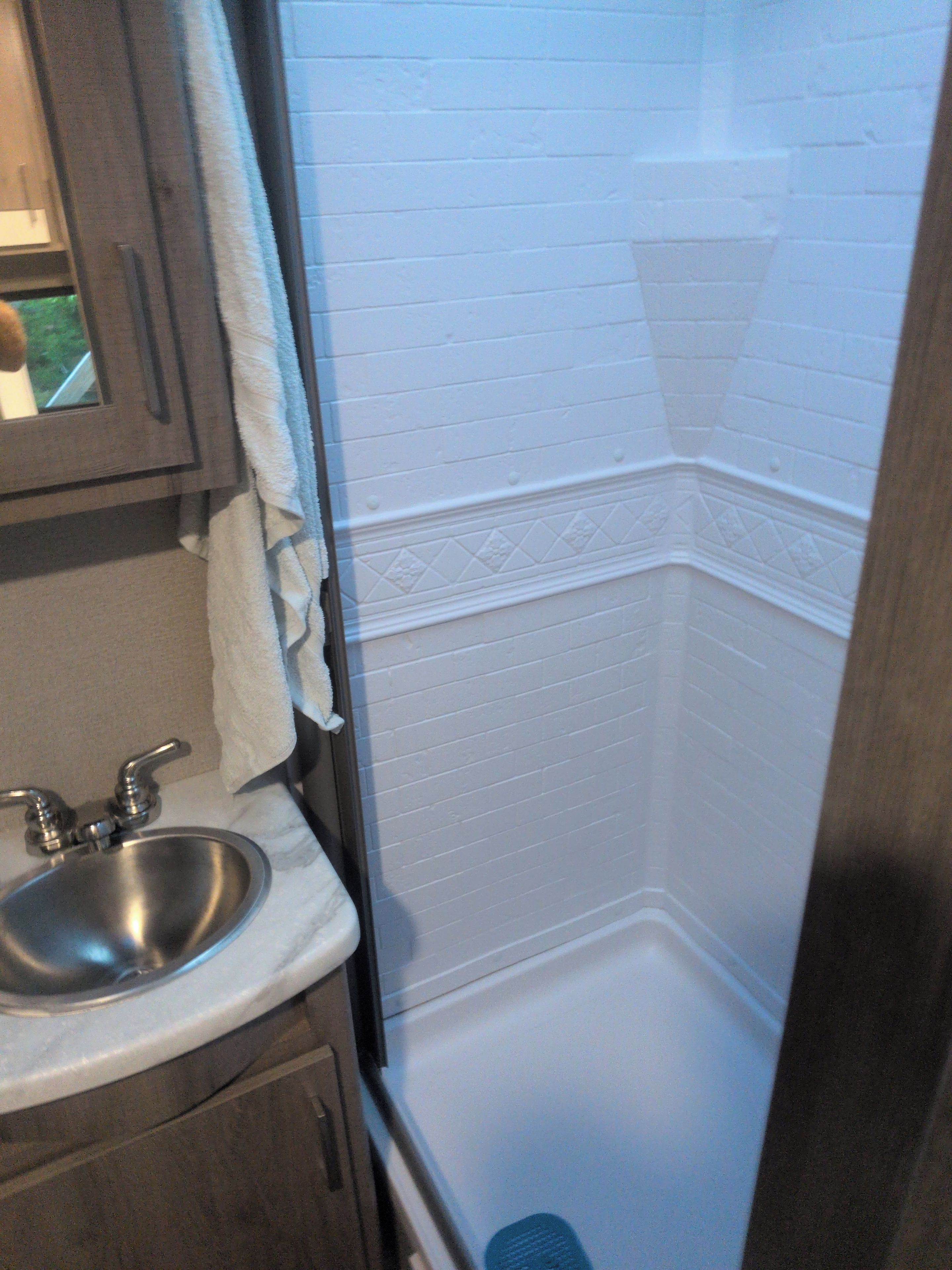 A bathroom with a sink, mirror, and a shower area.