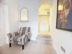 A room with a striped armchair, a white arched doorway, and a framed picture on the wall. - Stylish 2-Bed, Weybridge, Sleeps 4, Free Parking (Woburn Hill)