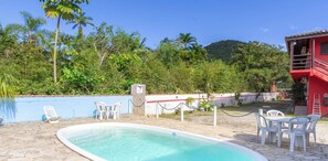 Une piscine avec des chaises longues et un bâtiment rouge en arrière-plan.