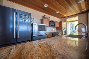 A modern kitchen with stainless steel appliances, wooden cabinets, and granite countertops. - Elua 103 - Lanai View of the ocean- 1 bedroom 2 bath (Kihei)