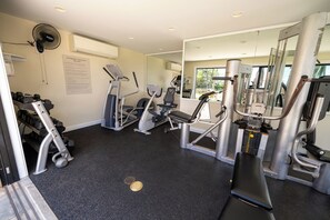 A fitness facility with cardio machines, weight machines, and a mirrored wall. - Elua 103 - Lanai View of the ocean- 1 bedroom 2 bath (Kihei)