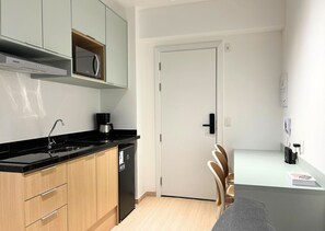 A compact kitchen with a microwave, coffee maker, and a dishwasher. - Nex One Edge Pinheiros by Housi (São Paulo)