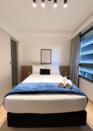 A hotel room with a large bed, a framed artwork on the wall, and a window with curtains. - Nex One Edge Pinheiros by Housi (São Paulo)