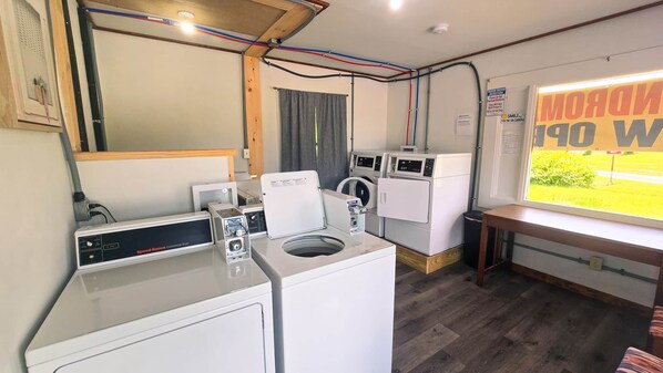 A laundry room with a Speed Queen commercial dryer, a front-loading washer, and a wall-mounted washing machine.