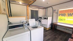 Une buanderie équipée d’un sèche-linge industriel Speed Queen, d’un lave-linge à chargement frontal et d’une machine à laver fixée au mur.