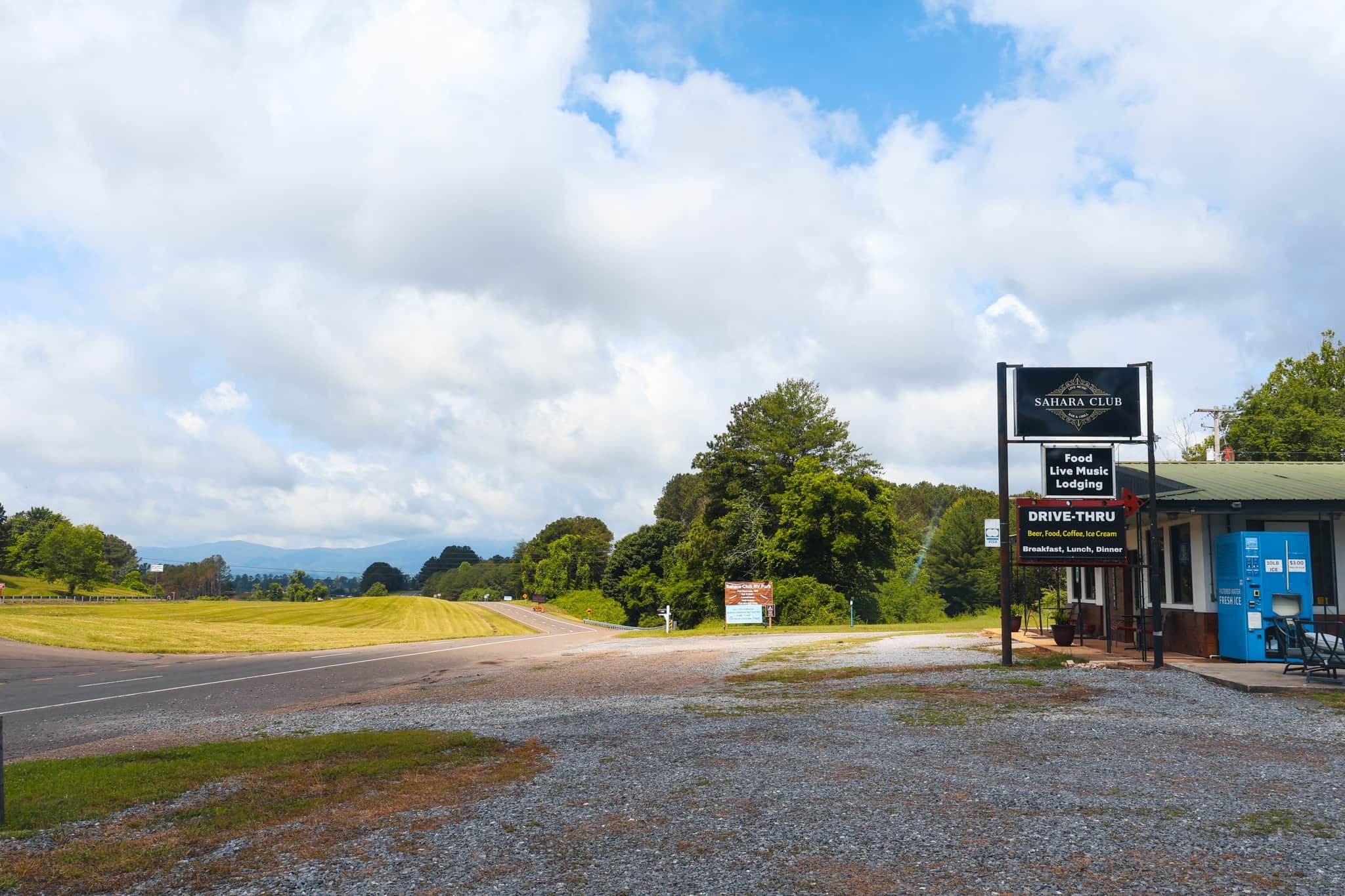 A roadside sign for Sahara Club, indicating food, live music, lodging, and drive-thru services.