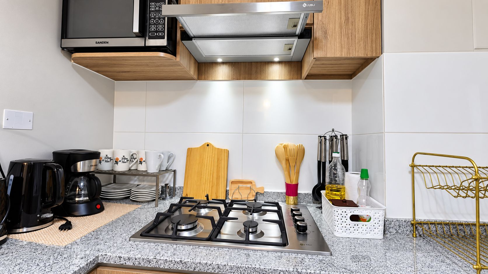 A modern kitchen with a gas stove, microwave, and stainless steel range hood.