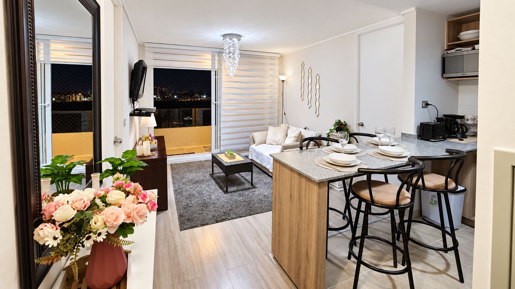 A modern kitchen with a central island, bar stools, and a dining area with a sofa and coffee table.