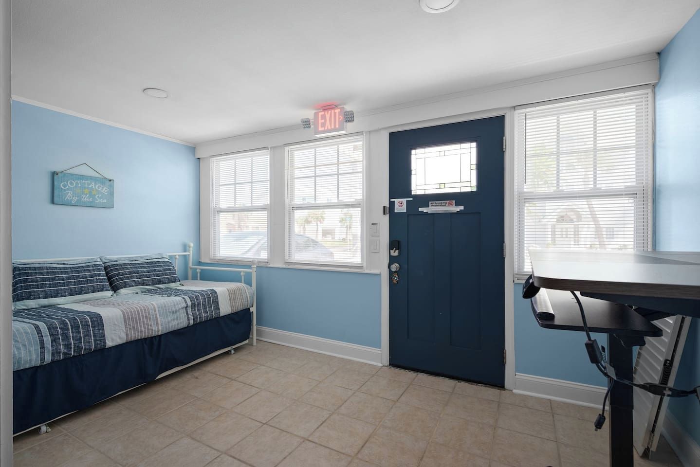 A bedroom with a bed, a desk, and a door with a window.