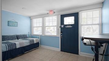 A bedroom with a bed, a desk, and a door with a window.