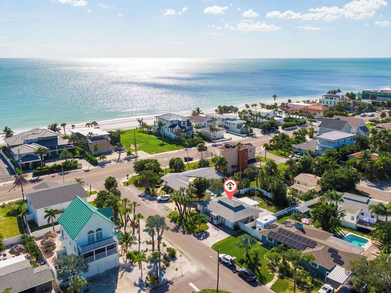 A coastal residential area with houses, a beach, and a clear view of the ocean.