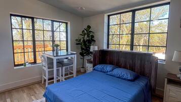 Une chambre à coucher avec un lit, un bureau et deux fenêtres.